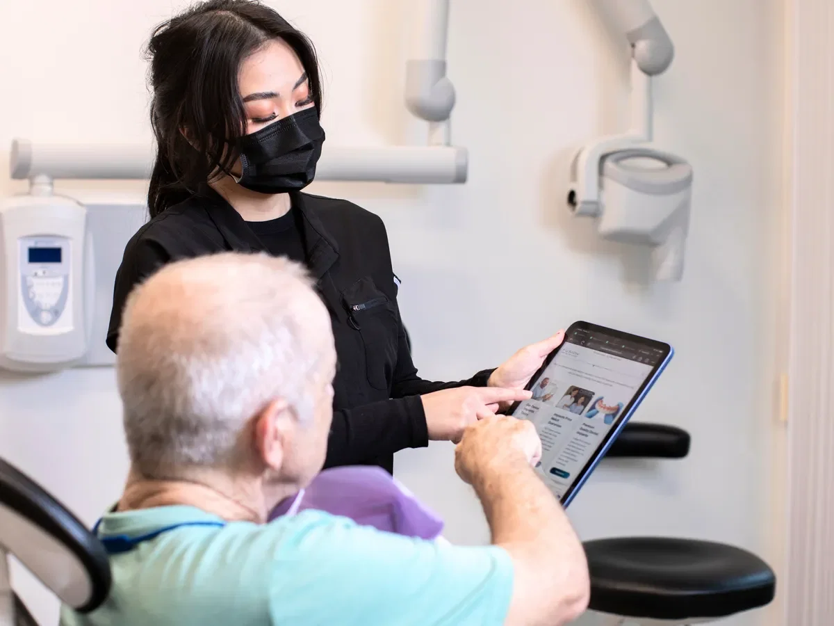 Patient reviewing All-on-4 vs All-on-6 options on tablet at Fusion Dental Implants consultation