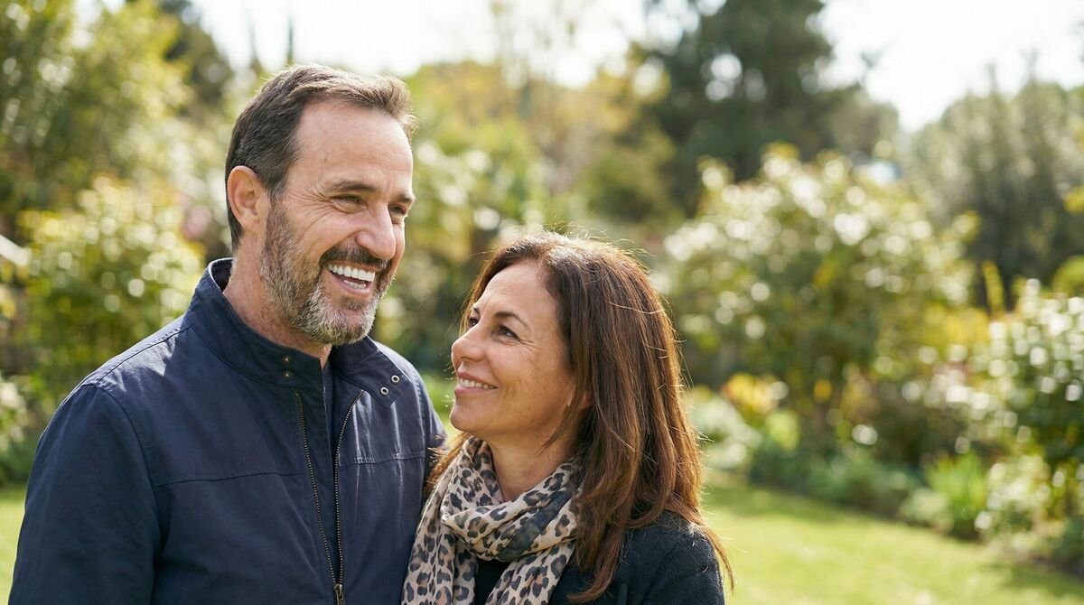 Happy man smiling confidently at a restaurant after full-arch dental implant restoration at Fusion Dental Implants