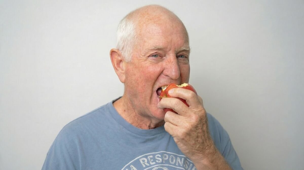 Happy patient biting into an apple after successful dental implant treatment at Fusion Dental Implants