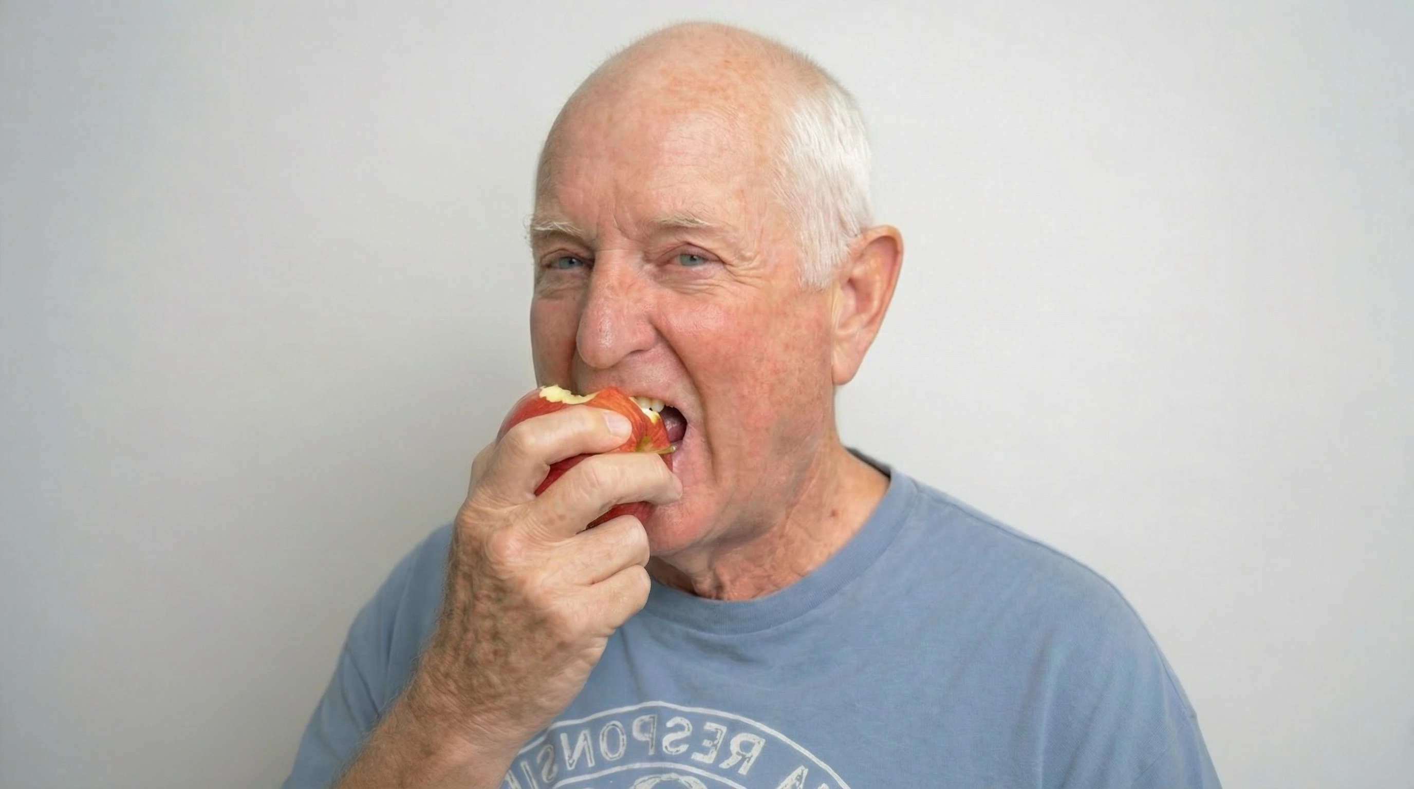 An older adult eating an apple