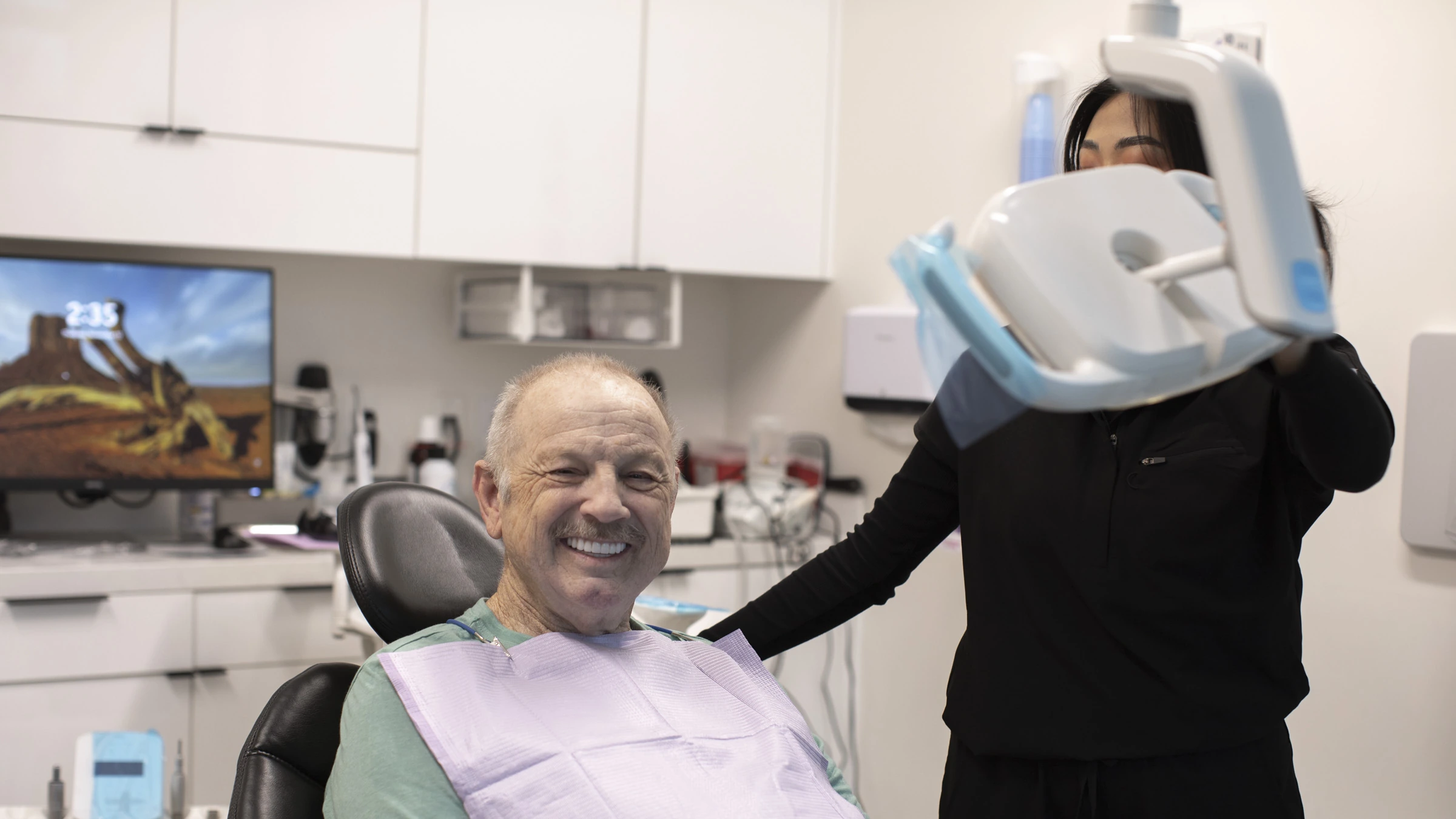 A smiling patient seated with the dental care team